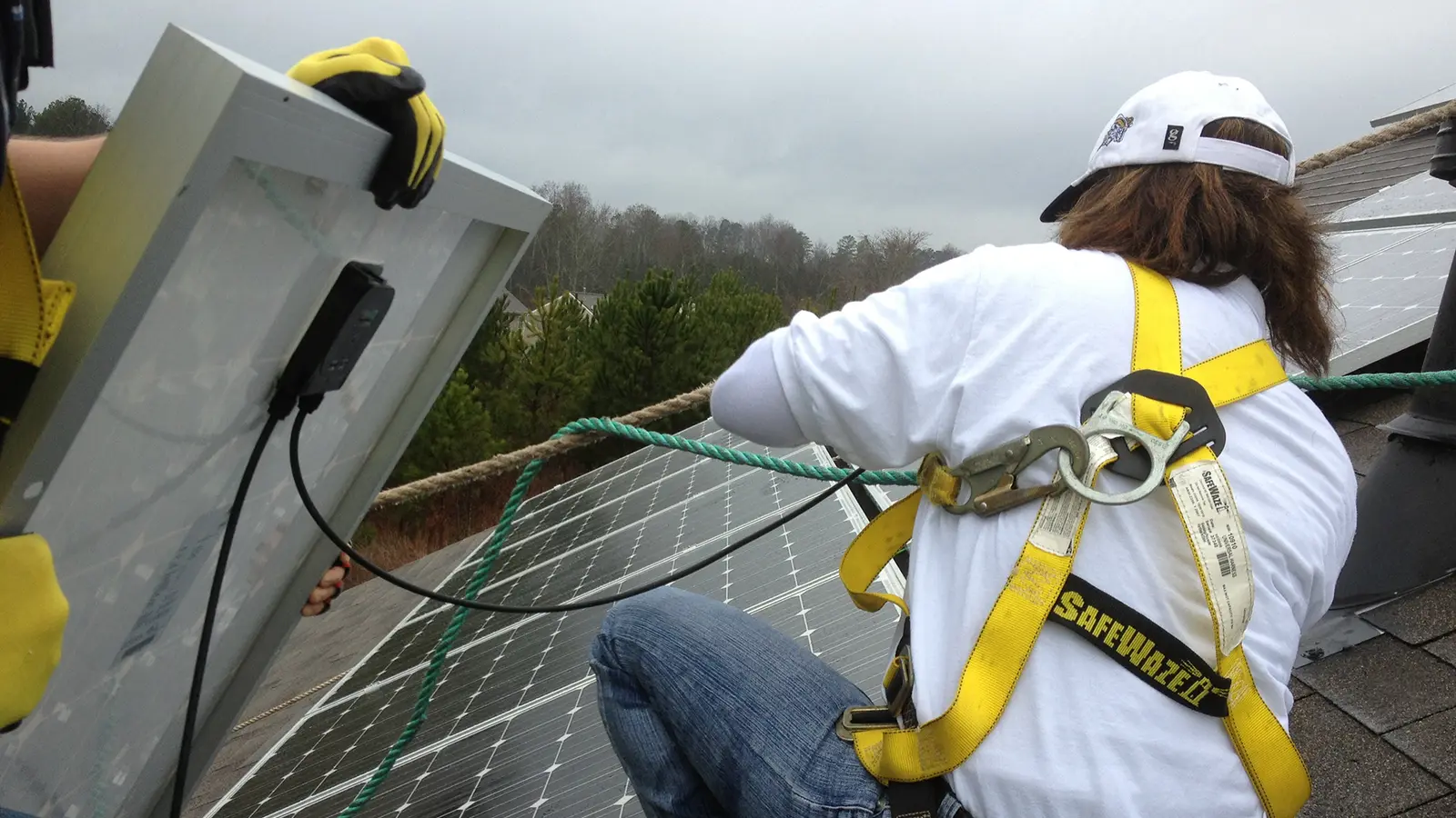 Installer in a safety harness working on a rooftop solar installation in Hiram, Georgia